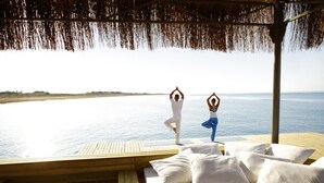 A wooden deck with a bed and pillows, overlooking a calm body of water and a distant shoreline. - ROBINSON NOBILIS - All Inclusive (Serik)