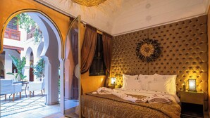 A bedroom with a large bed, a view of the courtyard, and a decorative wall. - Riad Wow (Marrakech)