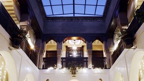 An interior with a skylight, ornate wooden doors, and wall-mounted lights. - Riad Wow (Marrakech)