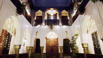 An interior with a central wooden door, arched windows, and hanging plants.