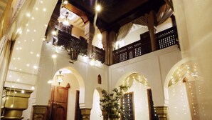 A multi-level interior with arched doorways, a chandelier, and string lights. - Riad Wow (Marrakech)