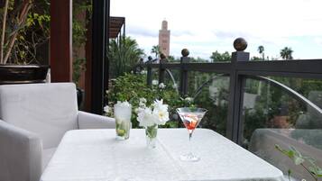 A table with a white tablecloth, two vases with flowers, and a martini glass with a red drink.