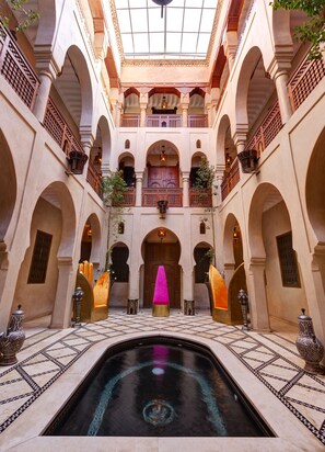 A spacious courtyard with a central pool, arched walkways, and ornate railings. - Riad Wow (Marrakech)
