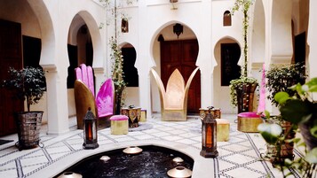 Un patio con arcos, una fuente y plantas en macetas.