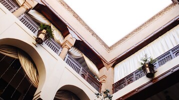 Un edificio con varios balcones, amplias ventanas con cortinas y columnas decorativas.