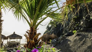 A beach with thatched umbrellas, a wooden deck, and a rocky cliff. - ROBINSON ÇAMYUVA Adults Only- All Inclusive (Kemer)