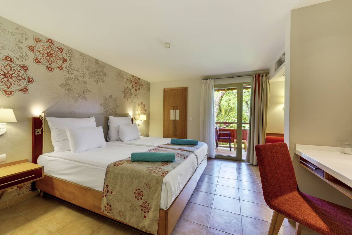 A hotel room with a large bed, two bedside tables, a desk, and a chair.