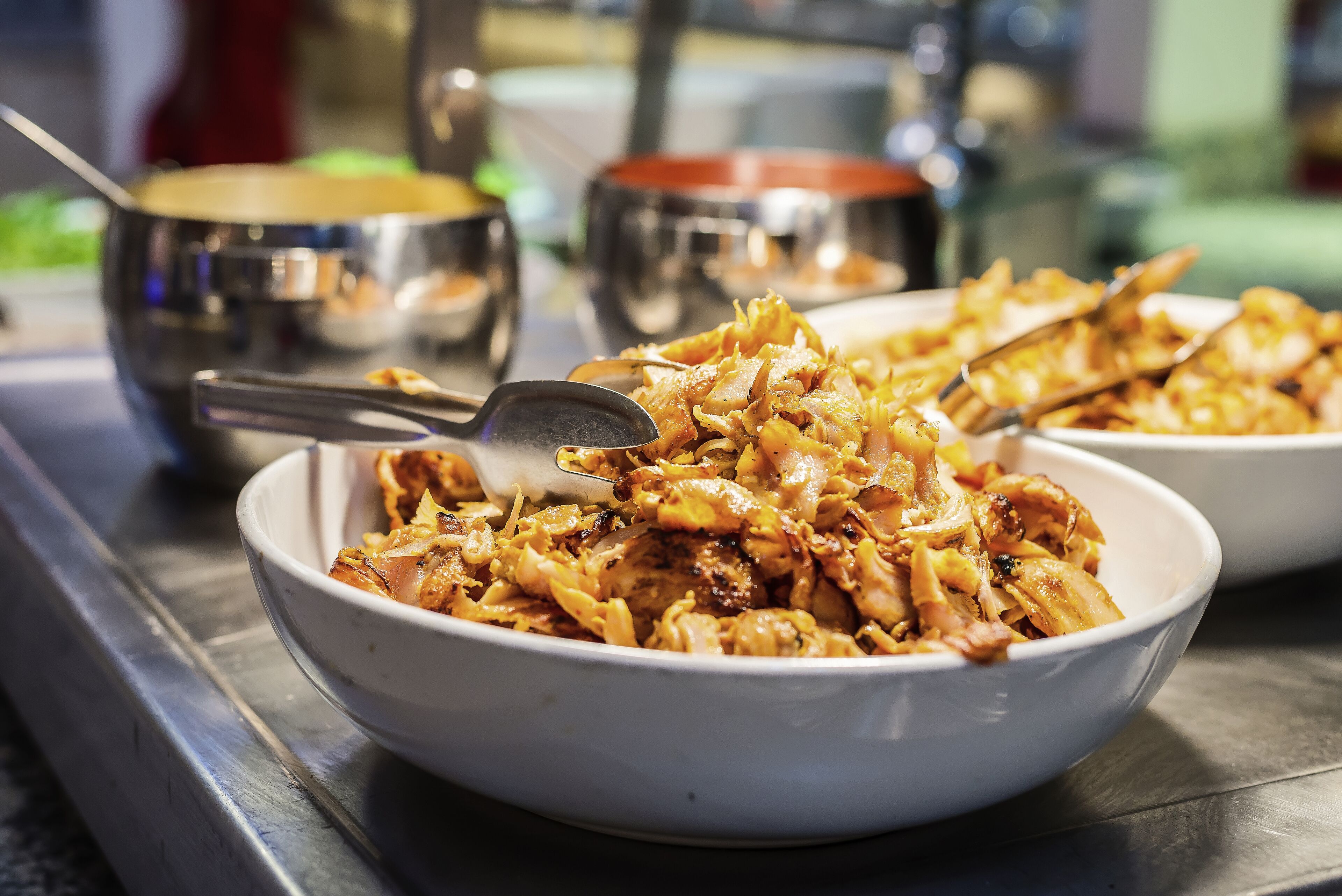 A dining table with two bowls of food, a spoon, and a metal bowl in the background.
