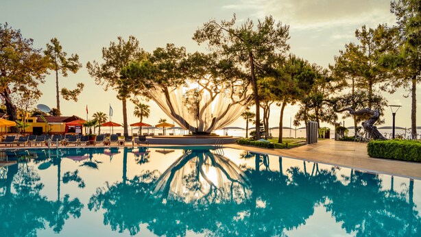 A pool with clear reflections of trees and a sunset. - ROBINSON ÇAMYUVA Adults Only- All Inclusive (Kemer)
