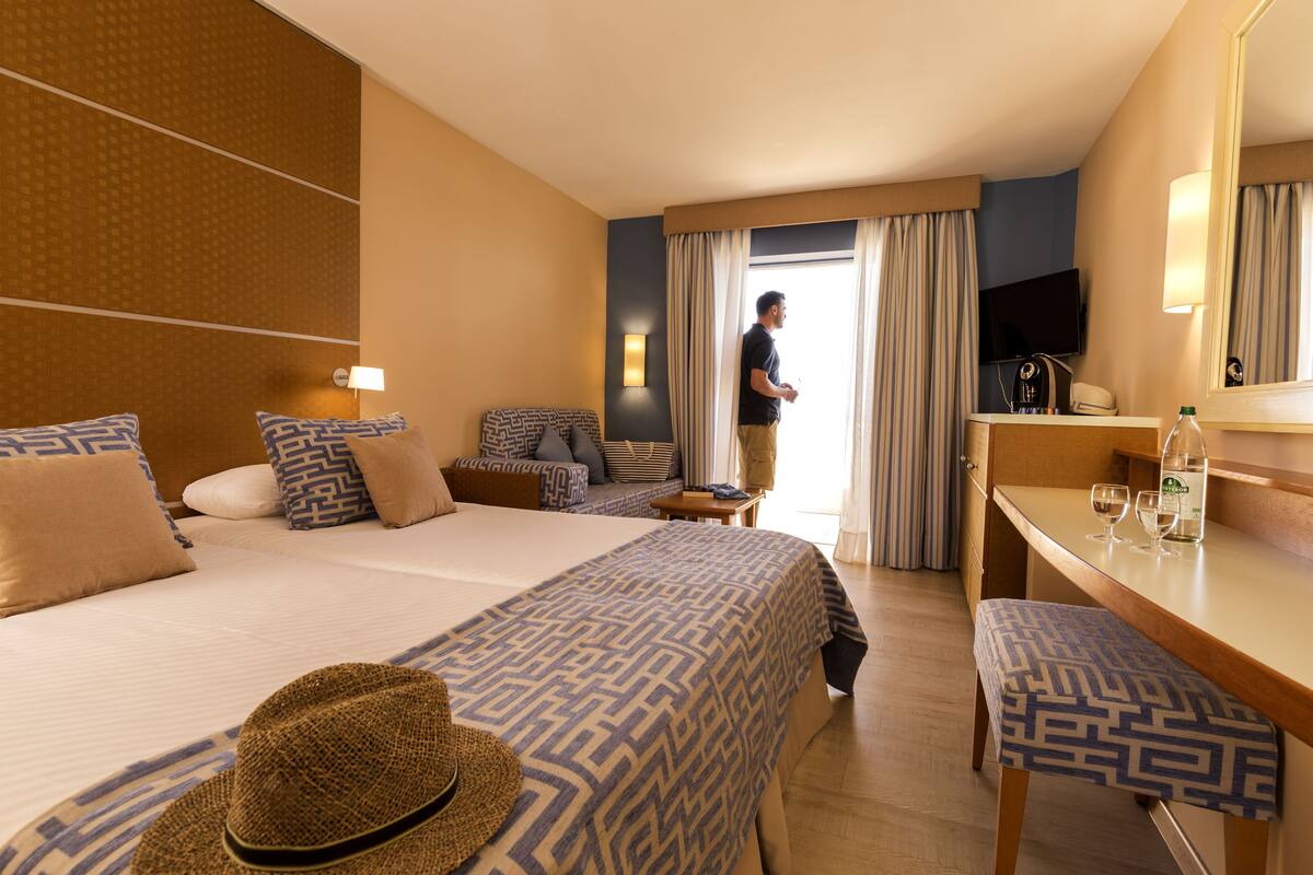 Une chambre d’hôtel avec un grand lit, un bureau, une télévision et une fenêtre avec des rideaux.