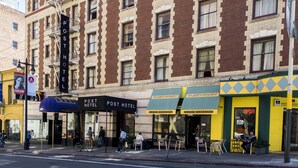 Un edificio con un letrero que indica el Post Hotel, una galería-café y un café llamado Honey.