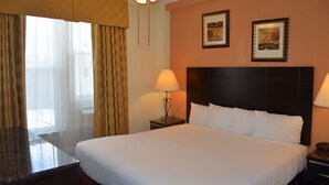 Una habitación de hotel con una cama grande, dos lámparas de noche, un cabecero y dos cuadros en la pared.