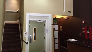 Vestíbulo de hotel con una escalera, una recepción y un reloj en la pared.