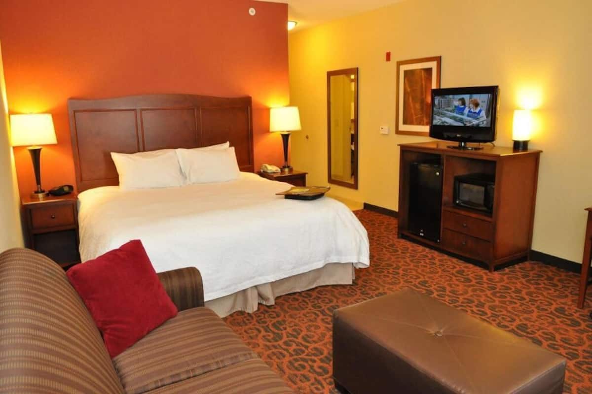 A hotel room with a bed, a television, a desk, and a couch.