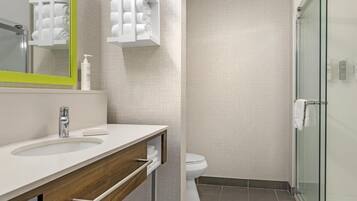Een moderne badkamer met een witte wastafel, spiegel en douchecabine van glas.