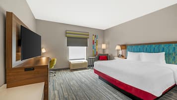 A hotel room with a large bed, a flat-screen TV, a desk, and a chair.