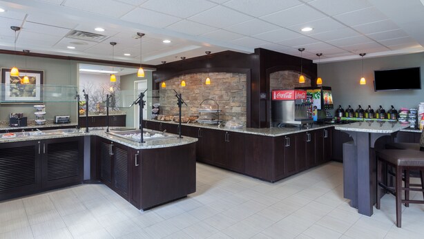 A modern kitchen with dark cabinetry, granite countertops, and pendant lighting. - Staybridge Suites North Brunswick by IHG (North Brunswick)