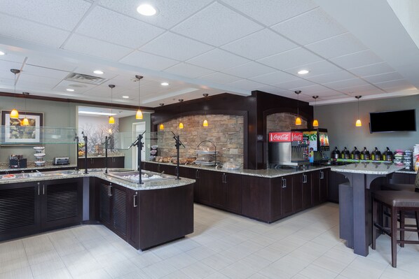 A modern kitchen with dark cabinetry, granite countertops, and pendant lighting. - Staybridge Suites North Brunswick by IHG (North Brunswick)