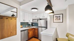 A compact kitchen with white cabinets, a stainless steel refrigerator, and a wooden countertop. - Staybridge Suites North Brunswick by IHG (North Brunswick)