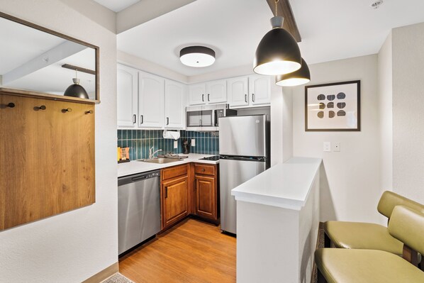 A compact kitchen with white cabinets, a stainless steel refrigerator, and a wooden countertop. - Staybridge Suites North Brunswick by IHG (North Brunswick)