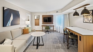 A modern hotel room with a sofa, a small round table, a desk with two chairs, a TV, and artwork on the walls. - Staybridge Suites North Brunswick by IHG (North Brunswick)