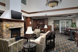 A hotel lobby with a fireplace, seating area, and a television mounted on the wall.