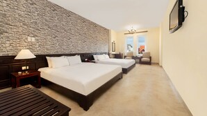 A hotel room with two beds, a stone wall, a TV, and a view of the outside. - Gold Coast Da Nang Hotel (Da Nang)