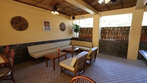 A restaurant with a stone wall, wooden furniture, and a ceiling fan. - Mermaid Resort Puerto Galera (Puerto Galera)