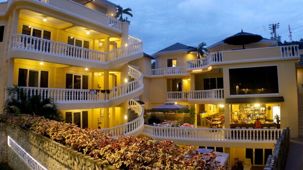 A multi-story hotel with balconies, a restaurant, and outdoor seating. - Mermaid Resort Puerto Galera (Puerto Galera)