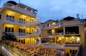 Um hotel com vários andares, varandas, restaurante e área externa para sentar.
