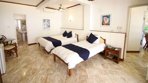 A hotel room with two beds, a small table with chairs, a bedside table with a phone, and a bathroom visible through an open door. - Mermaid Resort Puerto Galera (Puerto Galera)