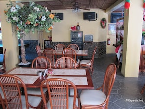 Ein Restaurant mit Holztischen und -stühlen, einer Steinsäule und einer Zierpflanze.