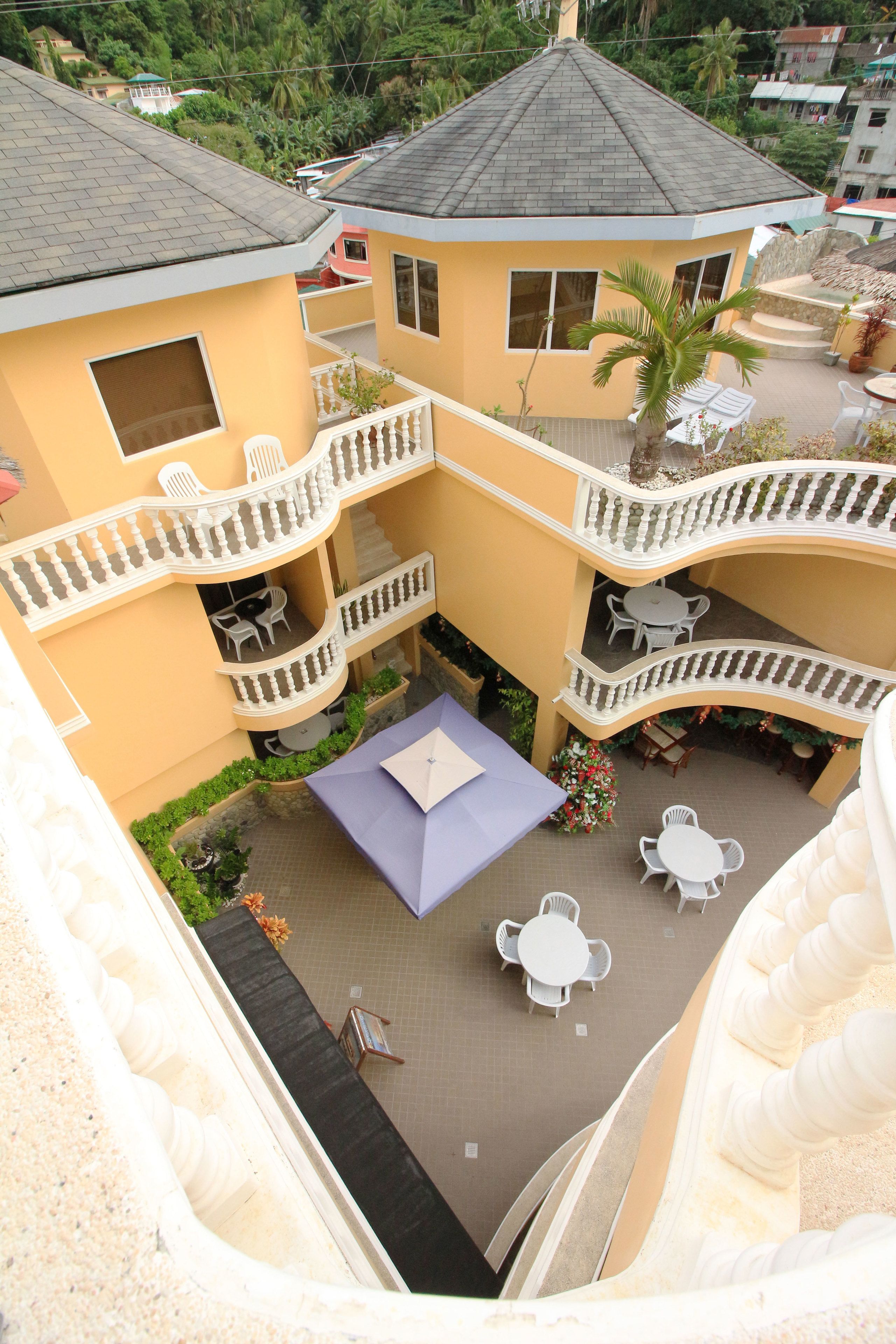 A multi-level building with balconies, outdoor seating, and a central patio area.