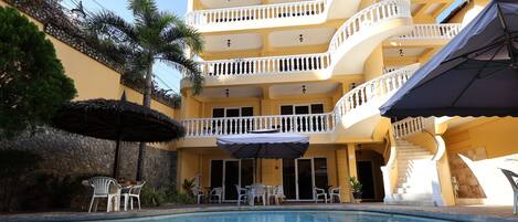 A hotel with a pool, outdoor seating, and a staircase.