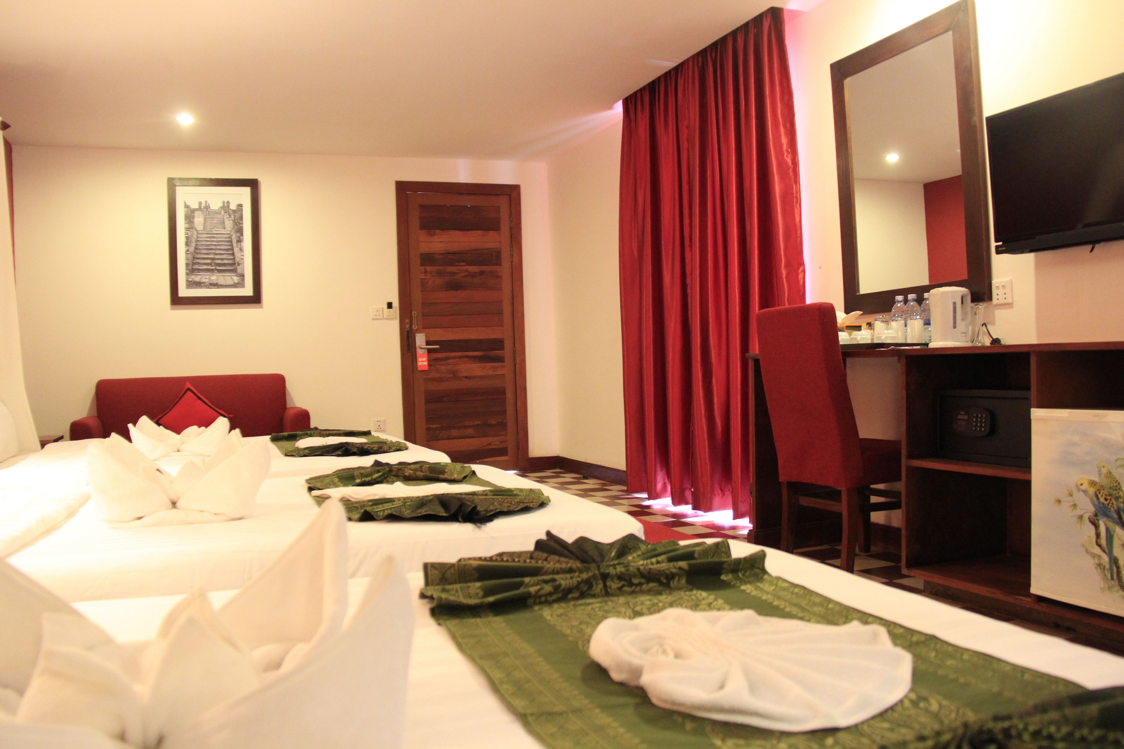 A hotel room with two beds, a desk, a chair, a television, and a framed picture on the wall.