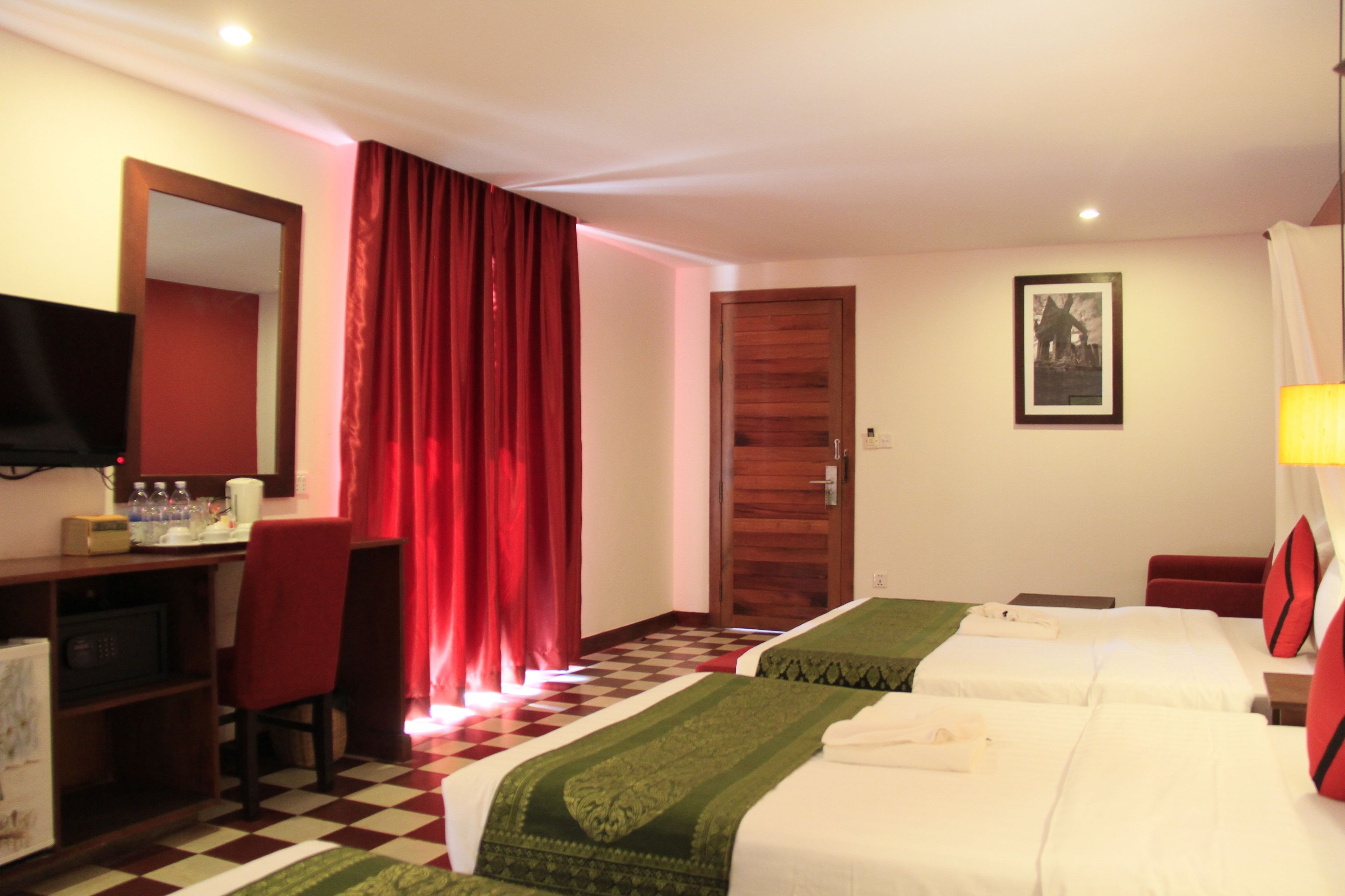 Une chambre d’hôtel avec deux lits, un bureau, une chaise, une télévision et une porte.