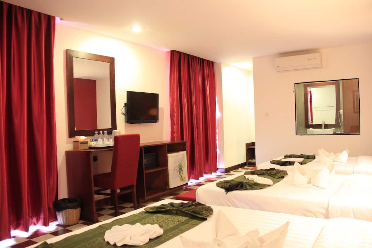 Habitación de hotel con dos camas, un escritorio con una silla, un televisor y un espejo grande.