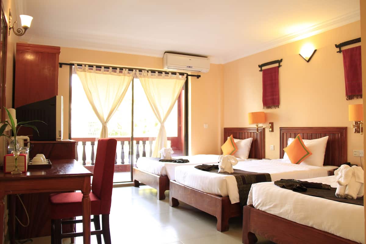 Habitación de hotel con dos camas, un escritorio, una silla y una ventana con cortinas.
