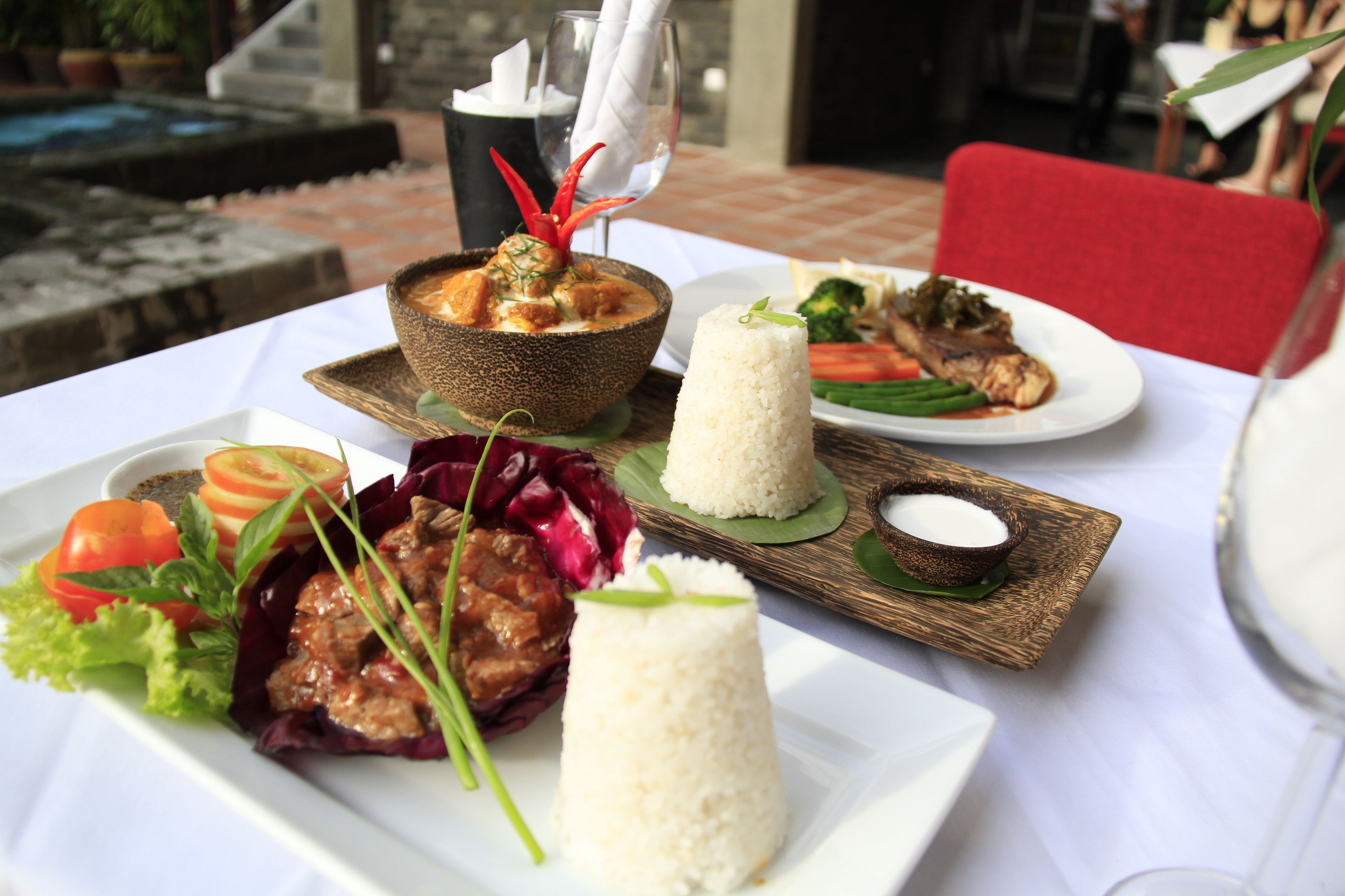 A table with various dishes including a bowl of curry, rice, and vegetables.