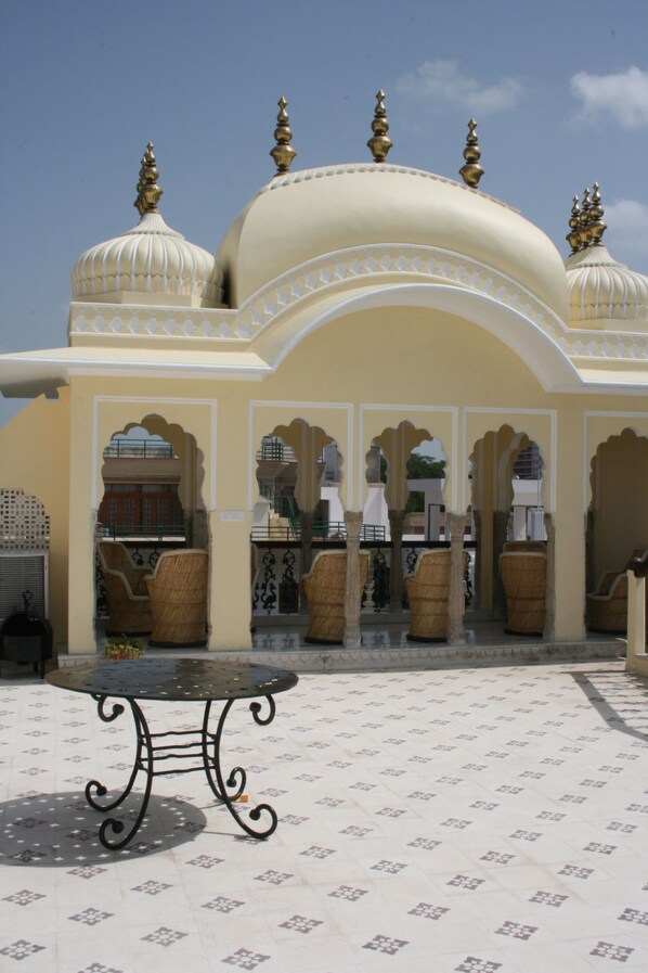 A courtyard with a table and chairs, a tiled floor, and a building with domes and arches. - Khandela Haveli A Heritage Boutique Hotel (Jaipur)