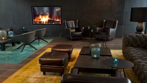 A modern living room with leather furniture, a fireplace, and a large TV screen. - Motel One München-Campus (Munich)