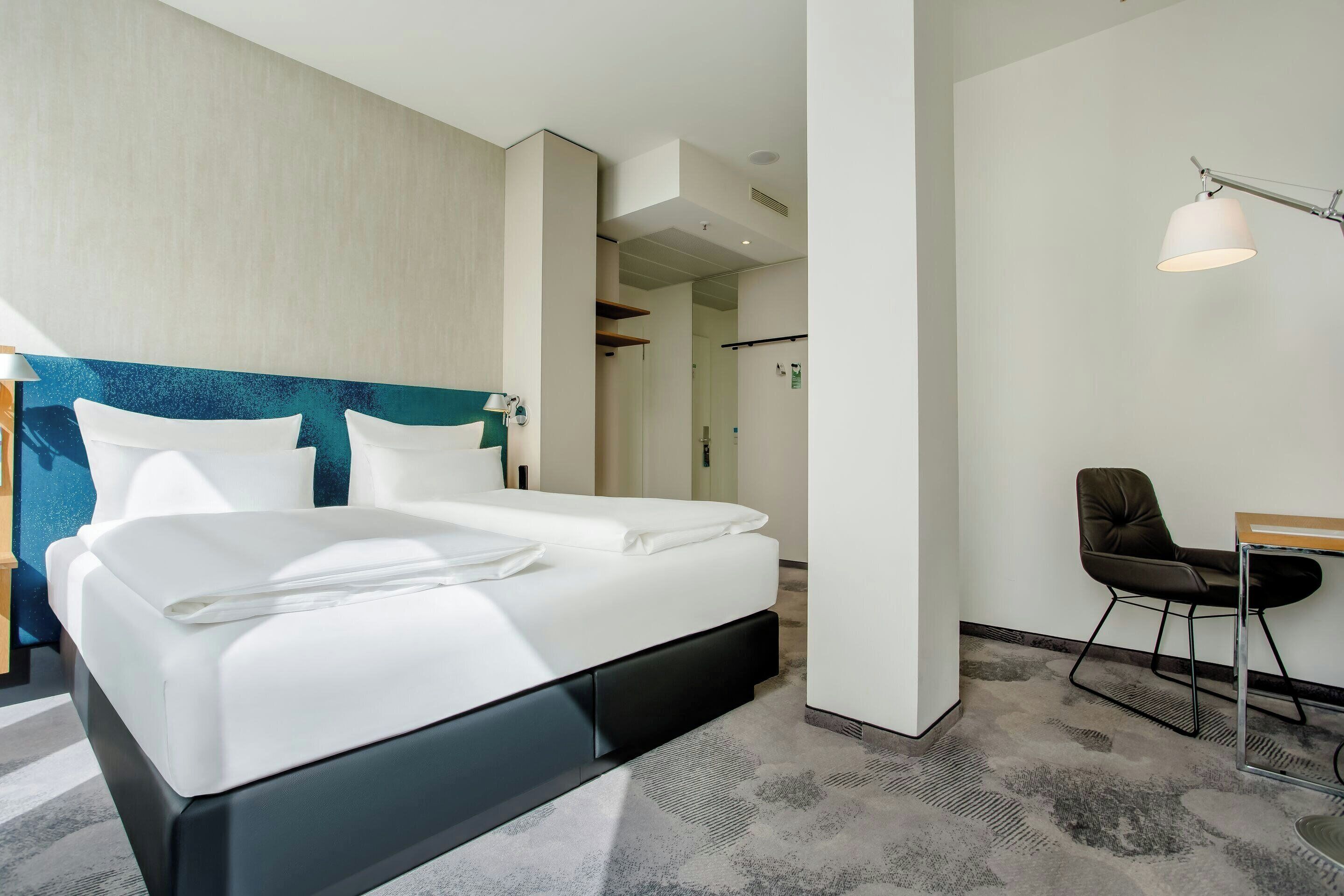 Una habitación de hotel moderna con una cama grande, un escritorio y una silla.