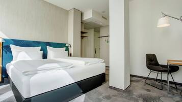 Una habitación de hotel moderna con una cama grande, un escritorio y una silla.