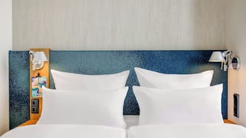 A hotel room with a bed, two white pillows, a headboard with a starry night design, and two wall-mounted lamps.