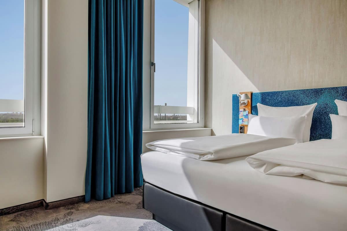 Una habitación de hotel con cama, ventana y vistas de la ciudad.