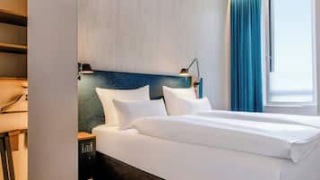 Une chambre d’hôtel avec un lit, une table de chevet, une lampe et une fenêtre avec des rideaux.