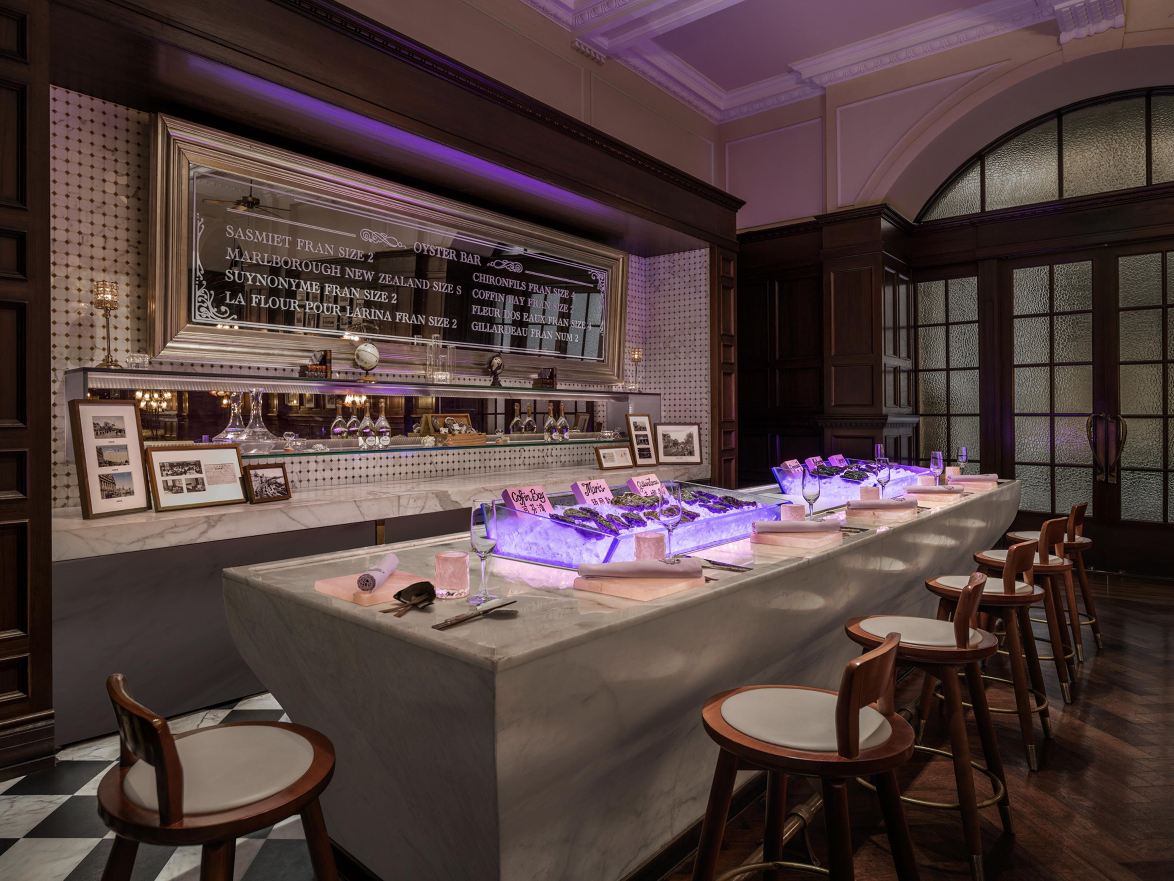 A bar area with a long counter, framed pictures, and a selection of bottles.