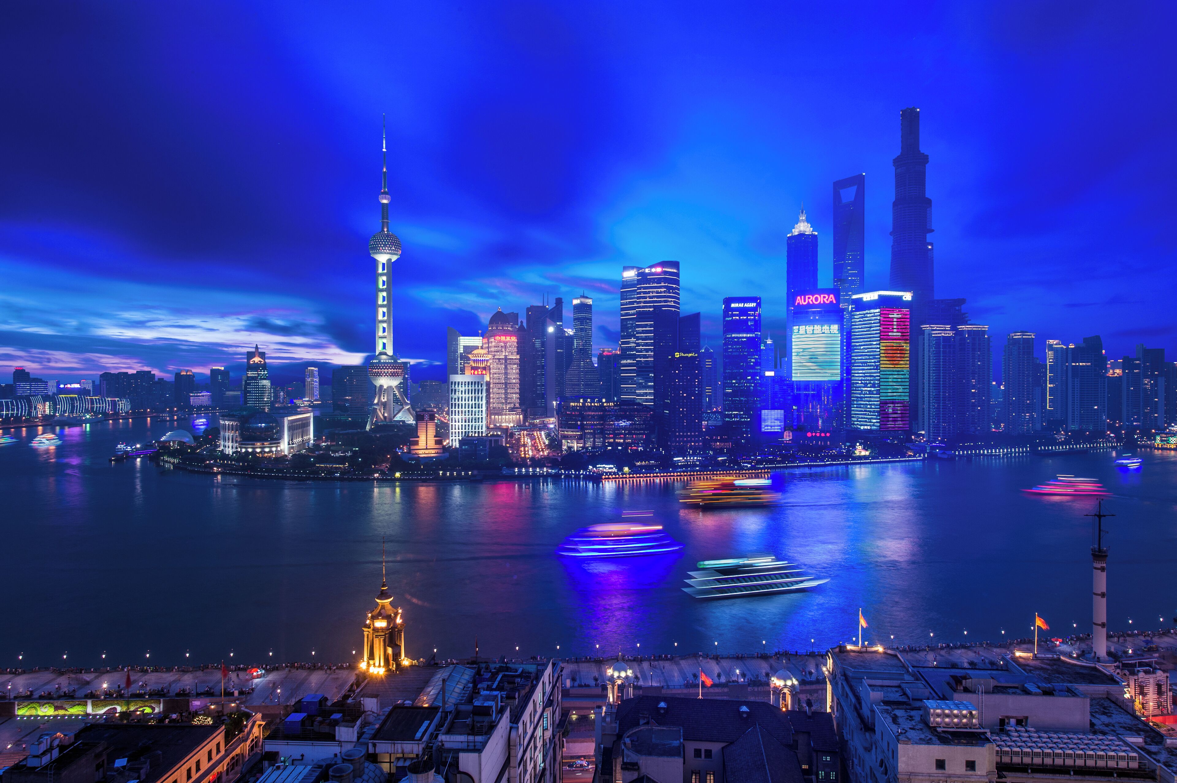A city skyline at night with illuminated buildings and a river.