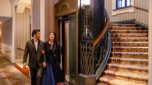 A grand staircase with ornate railings and floral-patterned carpet leading to an elevator. - Waldorf Astoria Shanghai on the Bund (Shanghai)