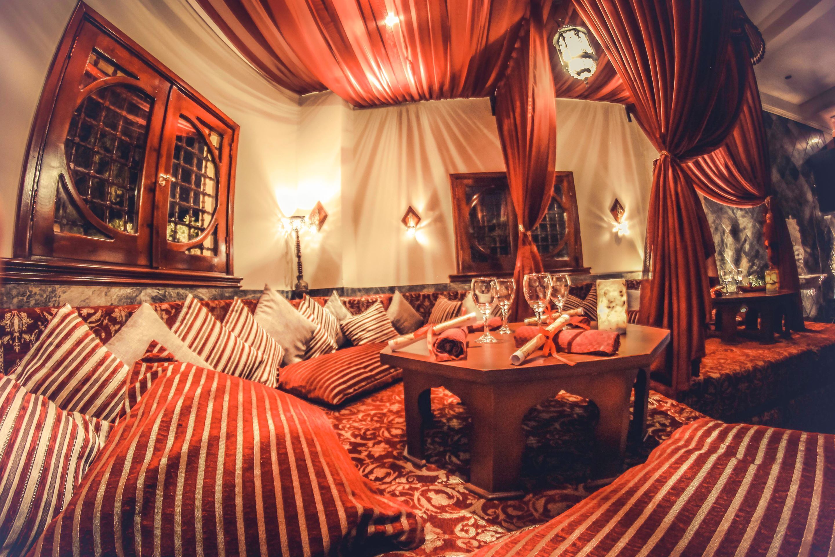 A cozy room with a sofa set, a table with glasses, and a large window with curtains.